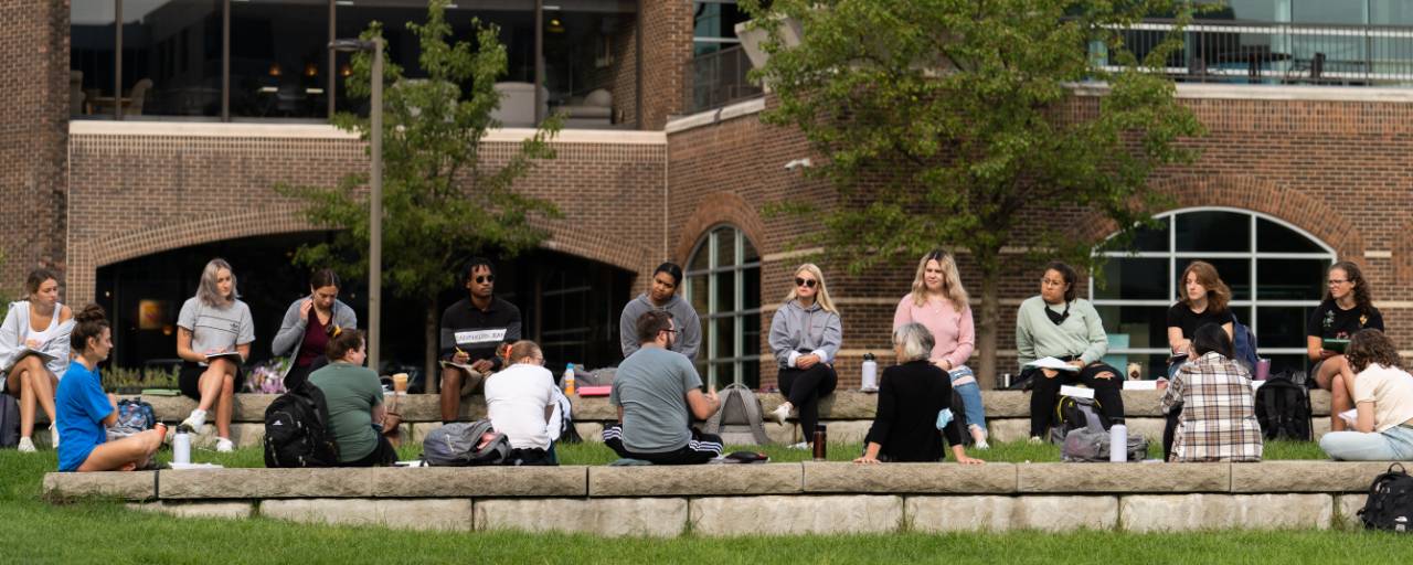 Students sitting on seats by the pond